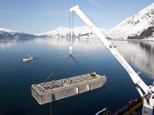 Small temporary storage barges, known as mini-barges, are used to hold the oil and oily water mix that would be offloaded to larger tank barges. The main support barge for nearshore recovery operation, known as the "500-2," has 12 such mini barges on board. The 500-2 is shown here setting one into the water during the Valdez training. Photo by Jeremy Robida.
