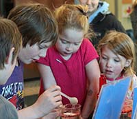 At the Homer oil spill Discovery Lab, a Homer student demonstrates the use of absorbents to soak up oil.