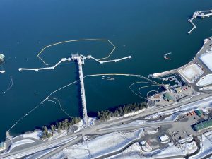 Photo taken on April 18 during an overflight of the Valdez Marine Terminal. Image shows several layers of oil spill boom, fishing vessels pulling current buster boom to collect oil. A sheen can be seen on the water inside the boom.