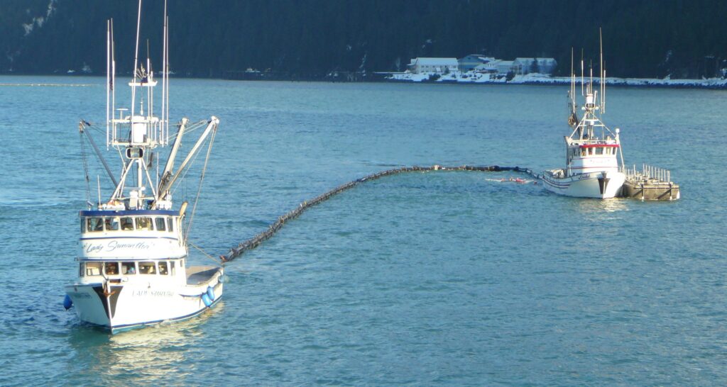 In this second image, two fishing vessels are again pulling boom behind them to form a curve. In this image, however, one boat is in front of the other so that the boom is in the shape of the letter J.