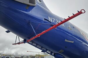 The photo shows the underside of an airplane with piping that is designed to spray liquid dispersants onto an oil spill.