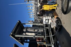 Four Alyeska employees wearing hard hats and protective gear stand in front of a palette of equipment that is about to be installed at Berth 4.